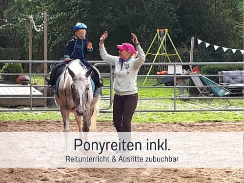 Una mujer y un niño en un caballo con las manos en alto. en Bio Ferienhof Wichtelweide - Fewo Lavendel, en Fehmarn