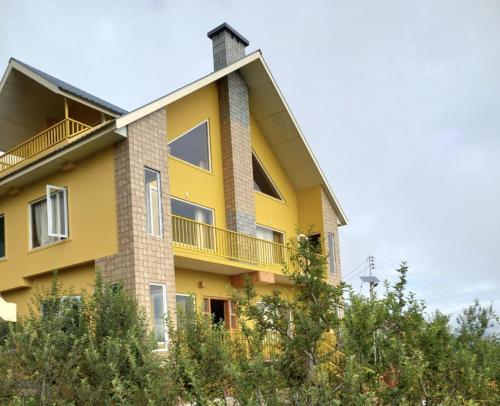 西姆拉的住宿－Forest Walk Cottage by Livingstone，黄色的建筑,旁边设有阳台