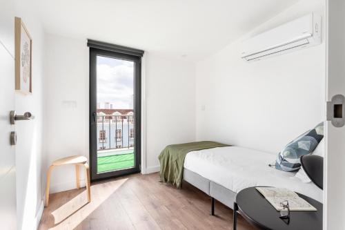 a white bedroom with a bed and a window at Lapa Duplex Apartment in Lisbon