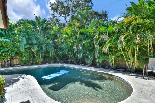 a swimming pool in a backyard with palm trees at Zen Pool Home in Lighthouse Point