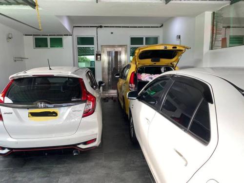 un garage avec deux voitures garées à l'intérieur dans l'établissement three bedroom tarraced house - RainaHomestay Pasir Gudang, à Pasir Gudang
