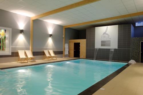 a large swimming pool with chairs in a building at Hotel Regina & Spa in Berck-sur-Mer