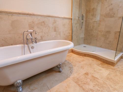 Wellington Lodge Cottage في ريتشموند: حمام مع حوض استحمام ودش ومرحاض