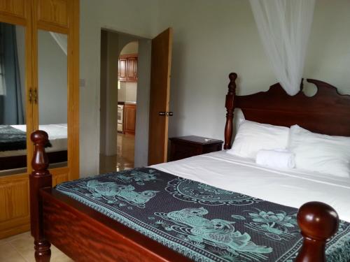 a bedroom with a bed with a wooden head board at Corosol Apartments in Roseau