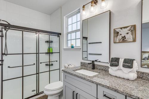 a bathroom with a toilet and a sink and a mirror at Modern Pensacola Vacation Home with Private Pool! in Pensacola