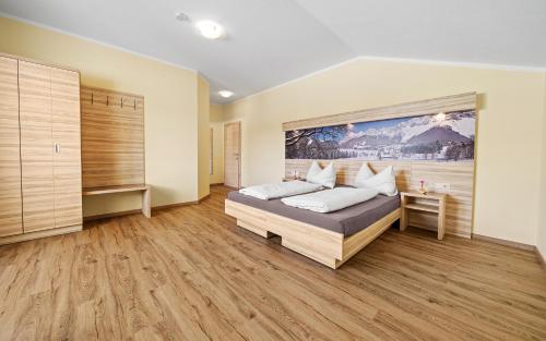 - une chambre avec un lit et une grande peinture murale dans l'établissement Luxus-Appartements Fosensteiner, à Ramsau am Dachstein