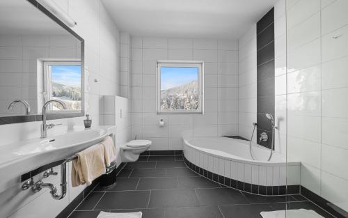 a bathroom with a tub and a toilet and a sink at Luxus-Appartements Fosensteiner in Ramsau am Dachstein