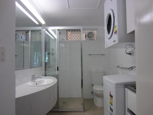 a bathroom with a shower and a sink and a toilet at Tradewinds McLeod Holiday Apartments in Cairns