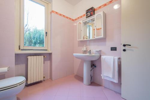 uma casa de banho rosa com um lavatório e um WC em Desenzanino Lakeside - 1 min from the beach em Desenzano del Garda