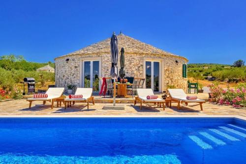 a villa with a pool in front of a house at Island Getaway - Heritage House with heated pool in Mirce