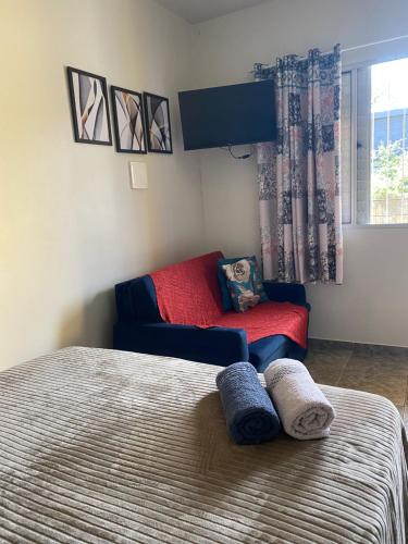 a bedroom with two beds and a red couch at Apartamento encantador cachoeira in Florianópolis