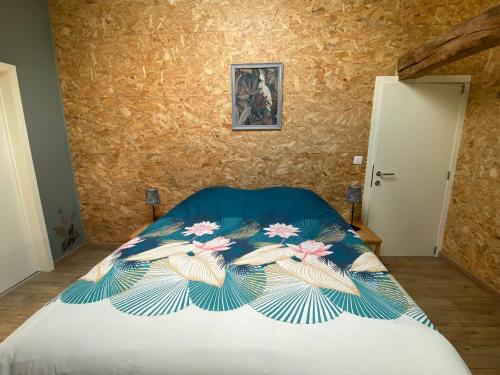 a bedroom with a bed with a floral bedspread at La demoiselle ô bois - Gite rural Chimay in Seloignes
