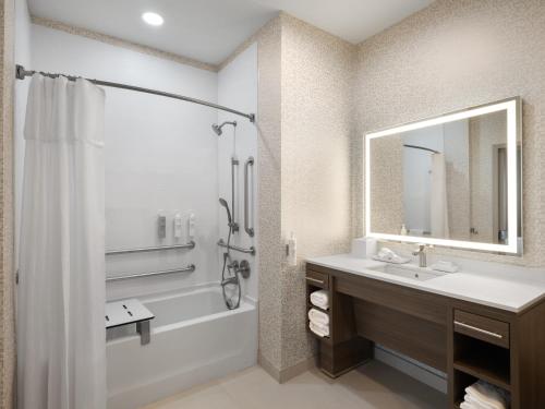 a bathroom with a tub and a sink and a mirror at Home2 Suites By Hilton Round Rock Medical Center in Round Rock
