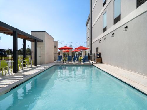 a swimming pool at a hotel with chairs and umbrellas at Home2 Suites By Hilton Round Rock Medical Center in Round Rock