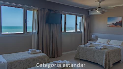 a bedroom with two beds and a view of the ocean at Hotel AATRAC in Mar del Plata