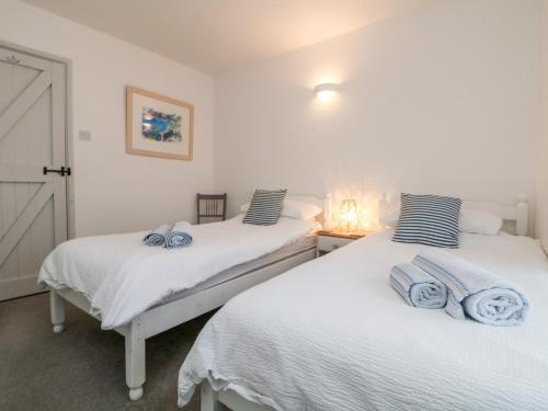 two beds in a room with white walls at Bell Cottage in Penzance