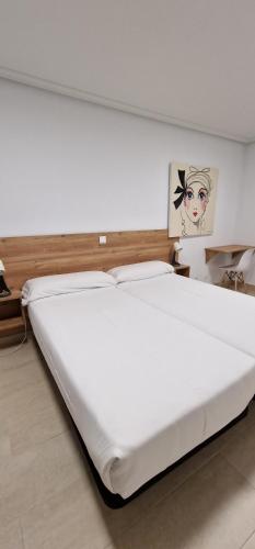 Apartamentos Gran Socaire de Noja في نوخا: سرير أبيض كبير في غرفة بها