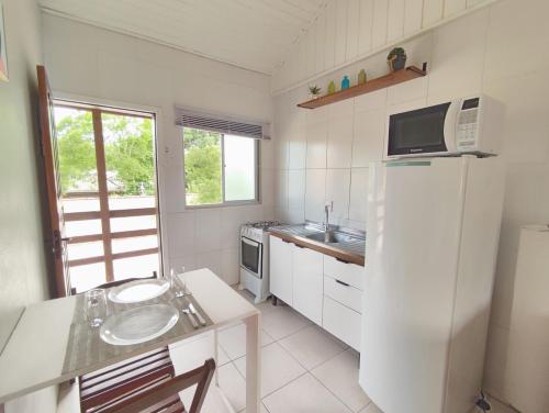 een witte keuken met een wastafel en een koelkast bij Residencial Barceloneta in Florianópolis