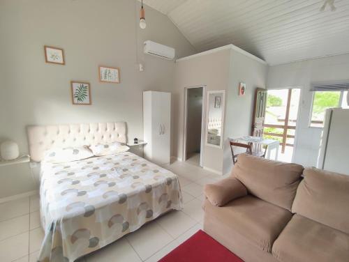 een slaapkamer met een bed en een bank bij Residencial Barceloneta in Florianópolis