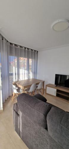 Apartamentos Gran Socaire de Noja في نوخا: غرفة معيشة مع طاولة وأريكة