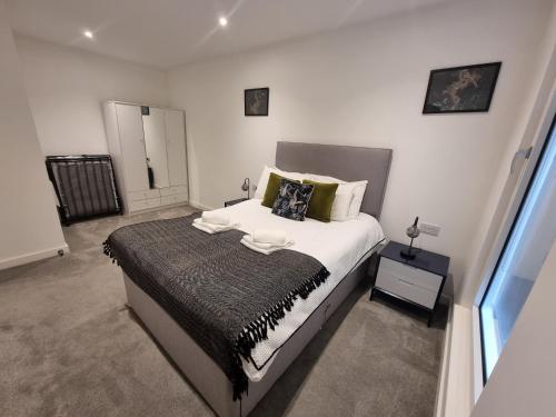 ein Schlafzimmer mit einem großen Bett und einem Fenster in der Unterkunft Trafford Suite Modern 1 bed with cinema room in Manchester