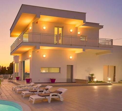 Un edificio con un montón de sillas y una piscina. en Luxurious Villa in Favara + Pool, en Favara