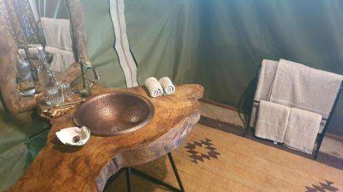 a bathroom with a copper sink on a wooden counter at Family Tent - Dolly Farm & River Camp in Usa River