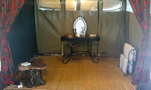 a room with a table in a tent with a mirror at Family Tent - Dolly Farm & River Camp in Usa River