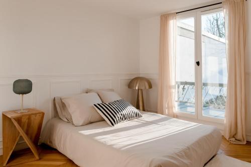 a white bedroom with a bed and a window at Logement entier ou à partager dans maison familiale à Rueil Malmaison, proche de Paris La Défense in Rueil-Malmaison