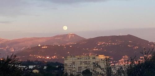 a moon over a city with a building and mountains at Chez Roland in Nice