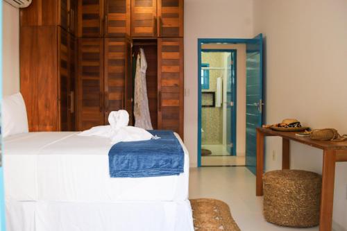 a bedroom with a white bed and a wooden door at Vila Marinella in Jericoacoara