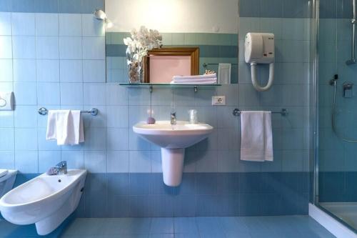 La salle de bains est pourvue de carrelage bleu, d'un lavabo et d'une douche. dans l'établissement Hotel Corallo, à Giulianova
