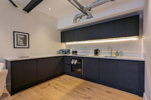 a kitchen with black cabinets and a sink at The Sunshade Suite Grade 2 Ancoats in Manchester