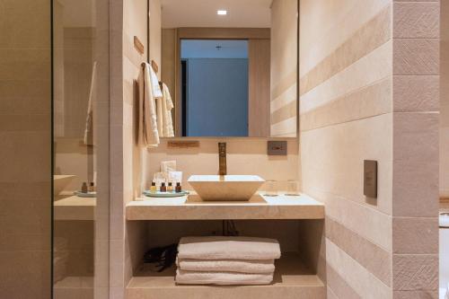 y baño con lavabo, espejo y toallas. en Nattivo Collection Hotel, en San Andrés