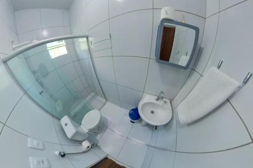 La salle de bains blanche est pourvue de toilettes et d'un miroir. dans l'établissement POUSADA CAMINHO do MAR, à Porto de Pedras