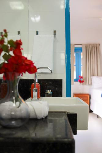 a bathroom with a sink and a vase with red flowers at Vila Marinella in Jericoacoara