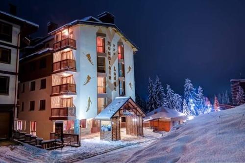 a large building in the snow at night at ELEA Apartment Mountain Lodge Pamporovo in Pamporovo