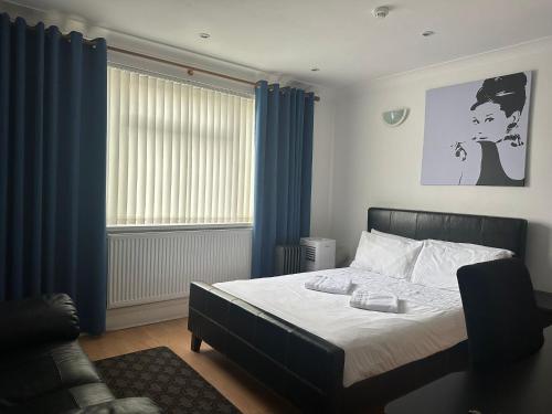 a bedroom with a bed with blue curtains and a couch at 3 Luxury En-suite Bedrooms in Cardiff