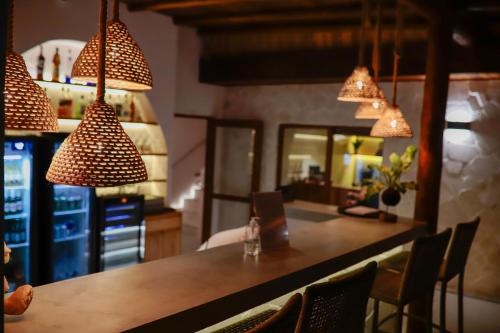 a kitchen with a table with chairs and pendant lights at AL MAR SUÍTES in Praia do Forte
