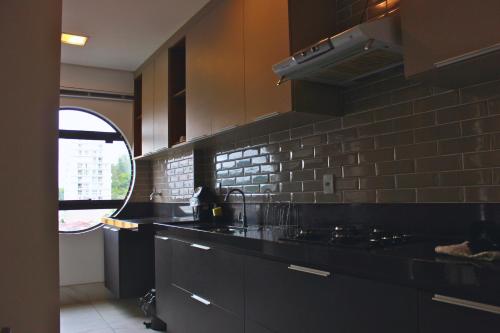 uma cozinha com balcões pretos e uma parede de tijolos em Gontijo Apart Hotel em Itajubá