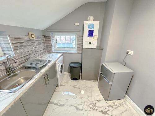 eine kleine Küche mit Spüle und Kühlschrank in der Unterkunft Modern 1 Bed Apartment In Morpeth Town Centre in Morpeth