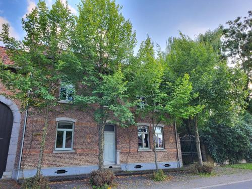 a brick building with trees in front of it at Charming and cosy ART DECO house in old historic farm with private natural pool and gardens with hiking and cycling trails nearby in Sint-Truiden