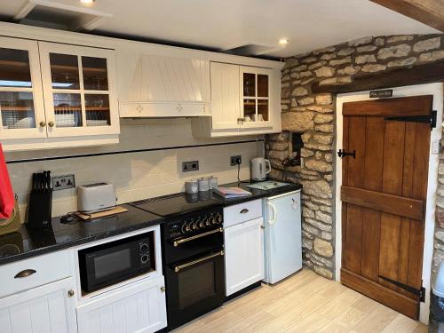 eine Küche mit weißen Geräten und einer Steinmauer in der Unterkunft Lavender Cottage, Grade 2 Listed Period Stone Built Cottage In Pickering, North Yorkshire in Pickering