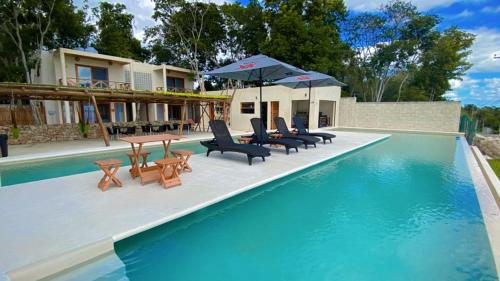 a swimming pool with chairs and tables and umbrellas at Hotel & Eco Cabañas Azul María Bacalar- Gratis Club de playa in Bacalar