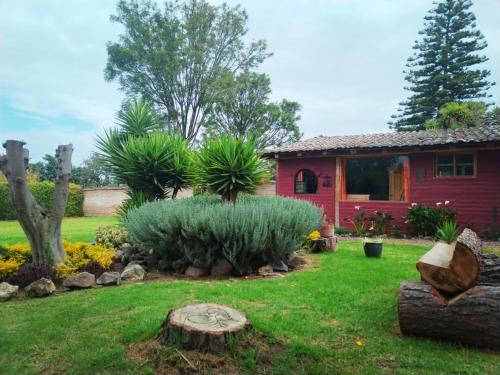 un jardín frente a una casa roja en Arie's Cabin, en Pifo