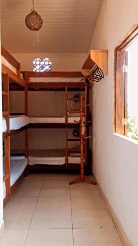a room with three bunk beds and a window at Hostel Aconchego do Arraial in Arraial d'Ajuda
