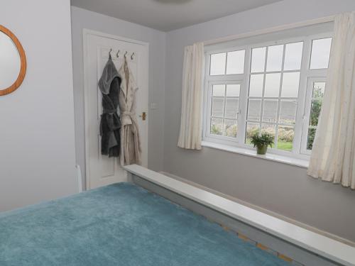 a bedroom with a blue rug and a window at Hen Felin Isaf in Llanddona