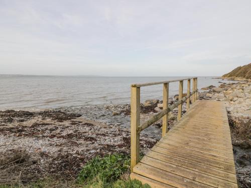 a wooden boardwalk leading to the water on a beach at Hen Felin Isaf in Llanddona