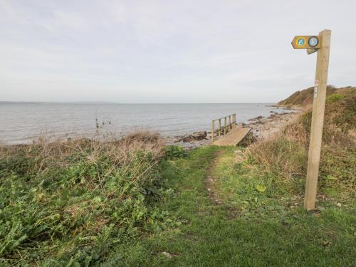 a sign on the side of a path next to the ocean at Hen Felin Isaf in Llanddona