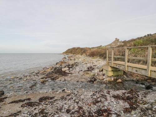 a bridge on a rocky beach next to the ocean at Hen Felin Isaf in Llanddona